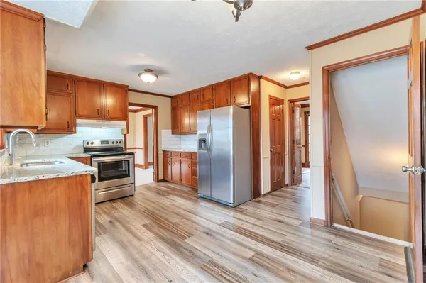 a kitchen with stainless steel appliances granite countertop a refrigerator a sink and a stove