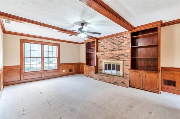wooden floor in an empty room with a fireplace and a window
