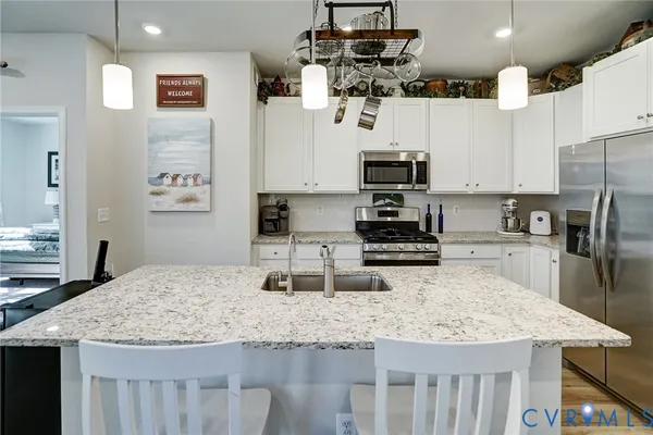 a view of kitchen island with granite countertop a sink a stove and wooden floor