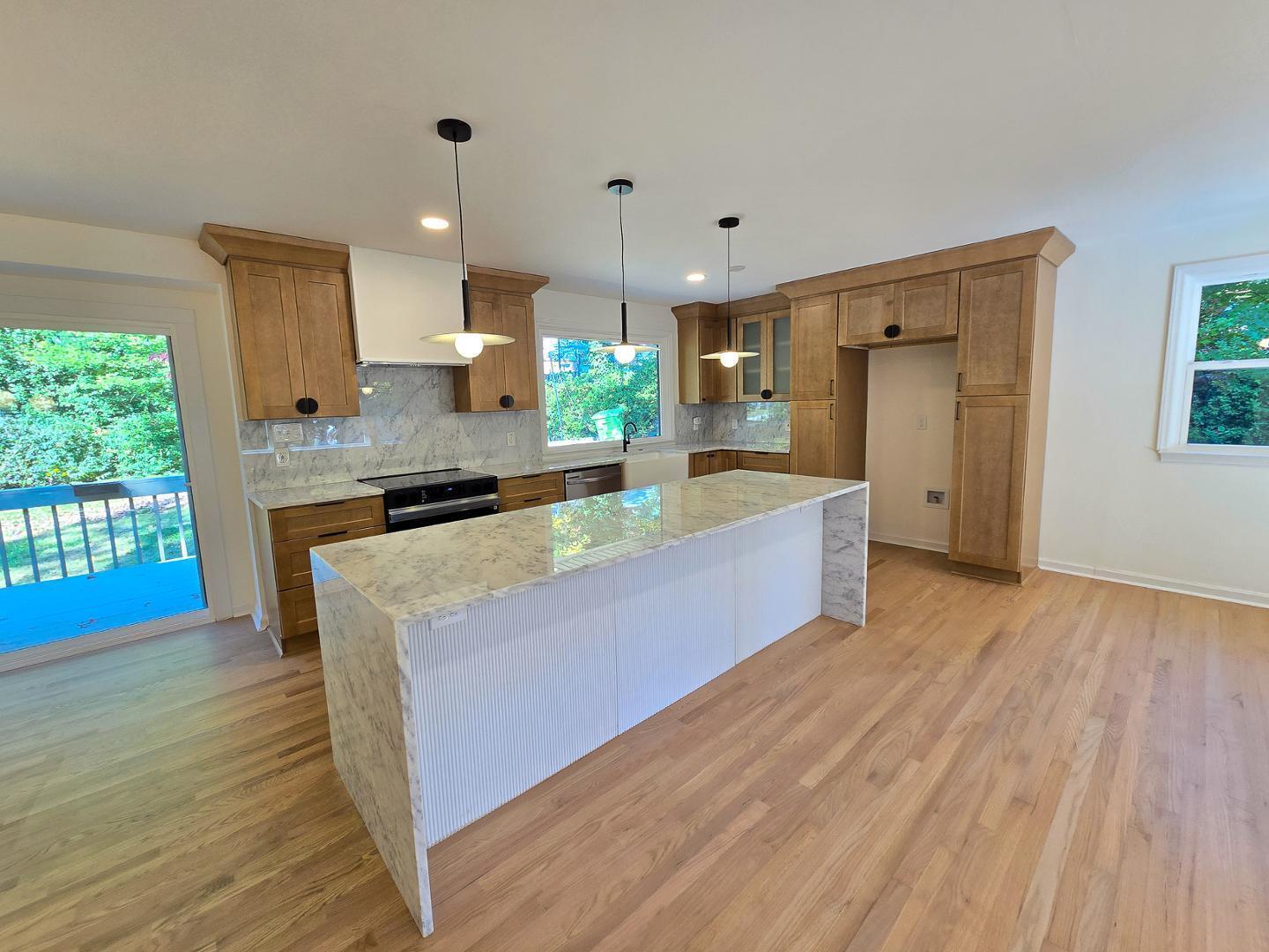 1105 Hardimont Road Raleigh, NC 27609 - Photo 8 of 61 a large kitchen with kitchen island a stove a sink dishwasher and wooden floor