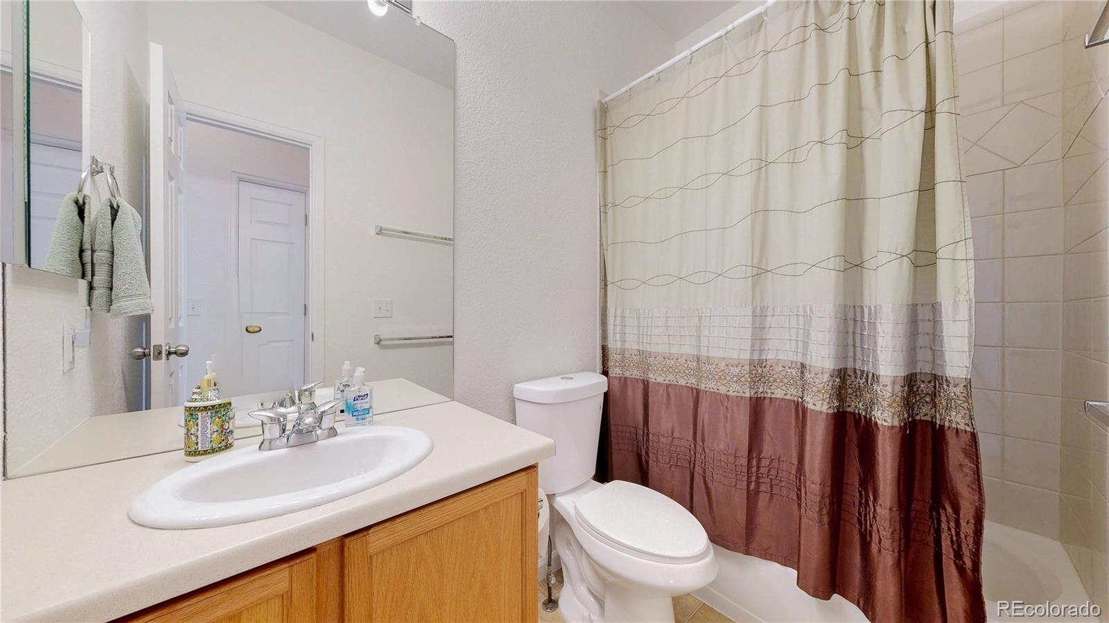 12237 Cook Court Thornton, CO 80241 - Photo 23 of 48 a bathroom with a sink a toilet and shower curtain