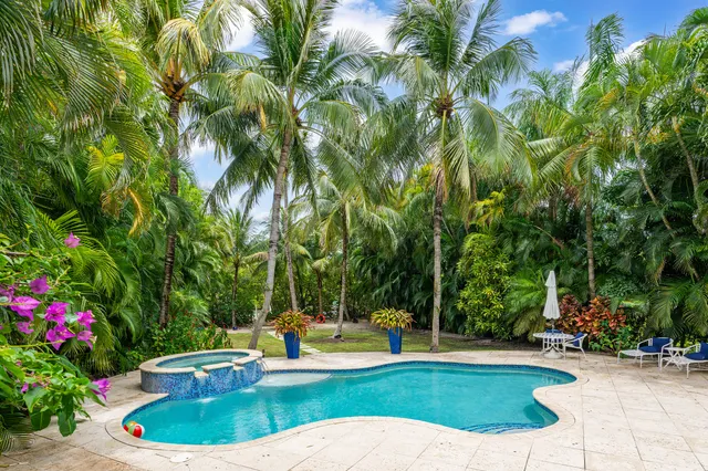a view of pool with lawn chairs and plants