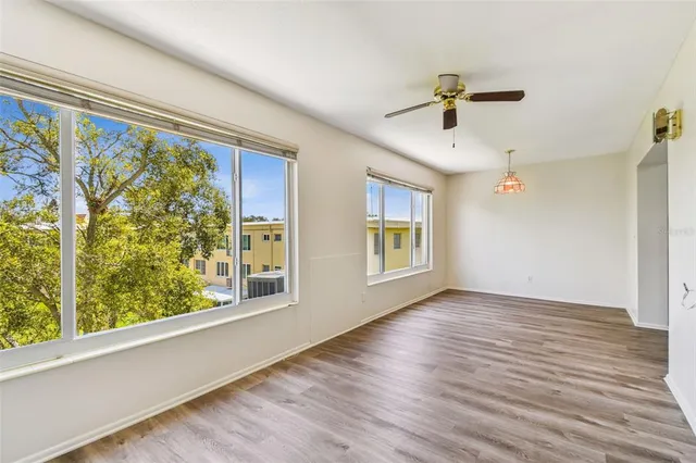 a view of empty room with wooden floor and fan