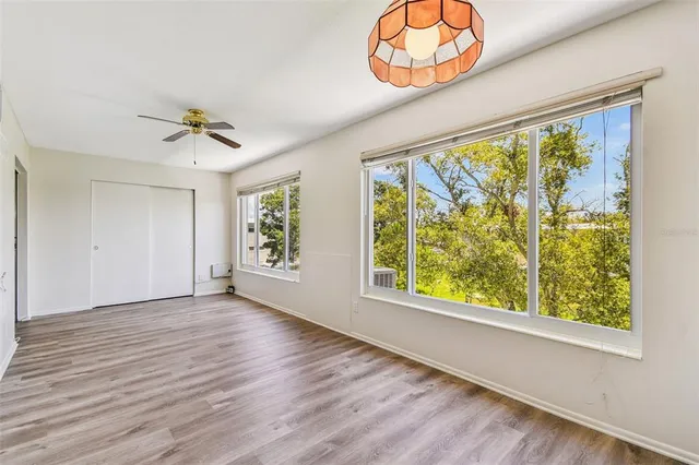 an empty room with wooden floor and ceiling fan