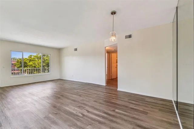 a view of an empty room with wooden floor and closet