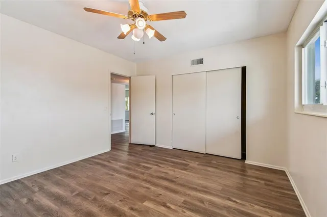 a view of an empty room with wooden floor and closet