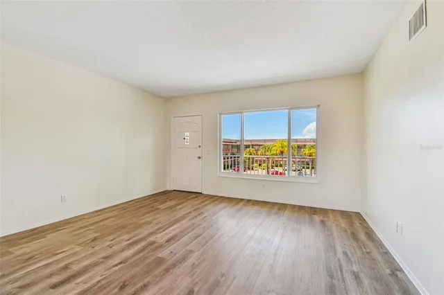a view of kitchen and empty room with wooden floor and windows