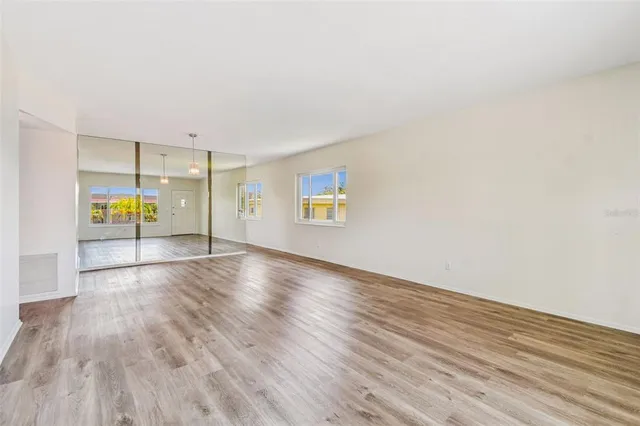 a view of an empty room with wooden floor and a window