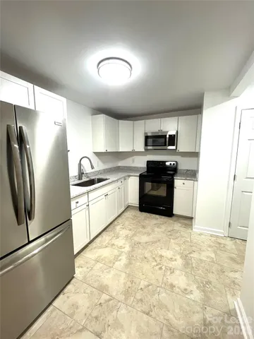 a kitchen with granite countertop a refrigerator and a sink