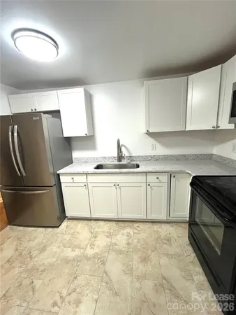 a kitchen with granite countertop a stove a sink and a refrigerator