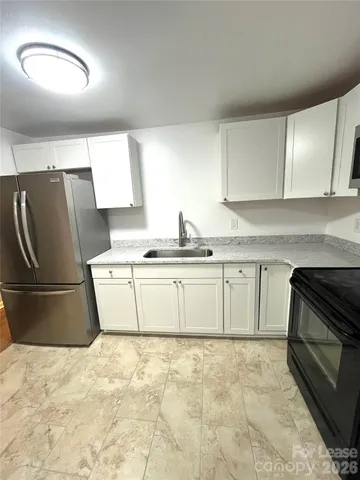 a kitchen with granite countertop a stove a sink and a refrigerator