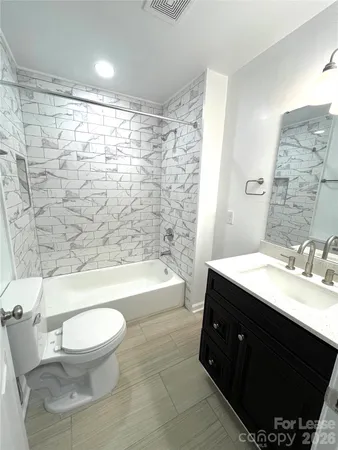 a bathroom with a bathtub shower sink mirror vanity and toilet