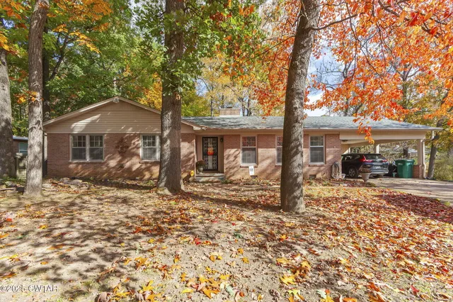 a front view of a house with a tree