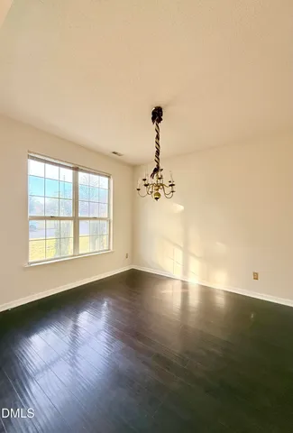 a view of an empty room with wooden floor fireplace and a window
