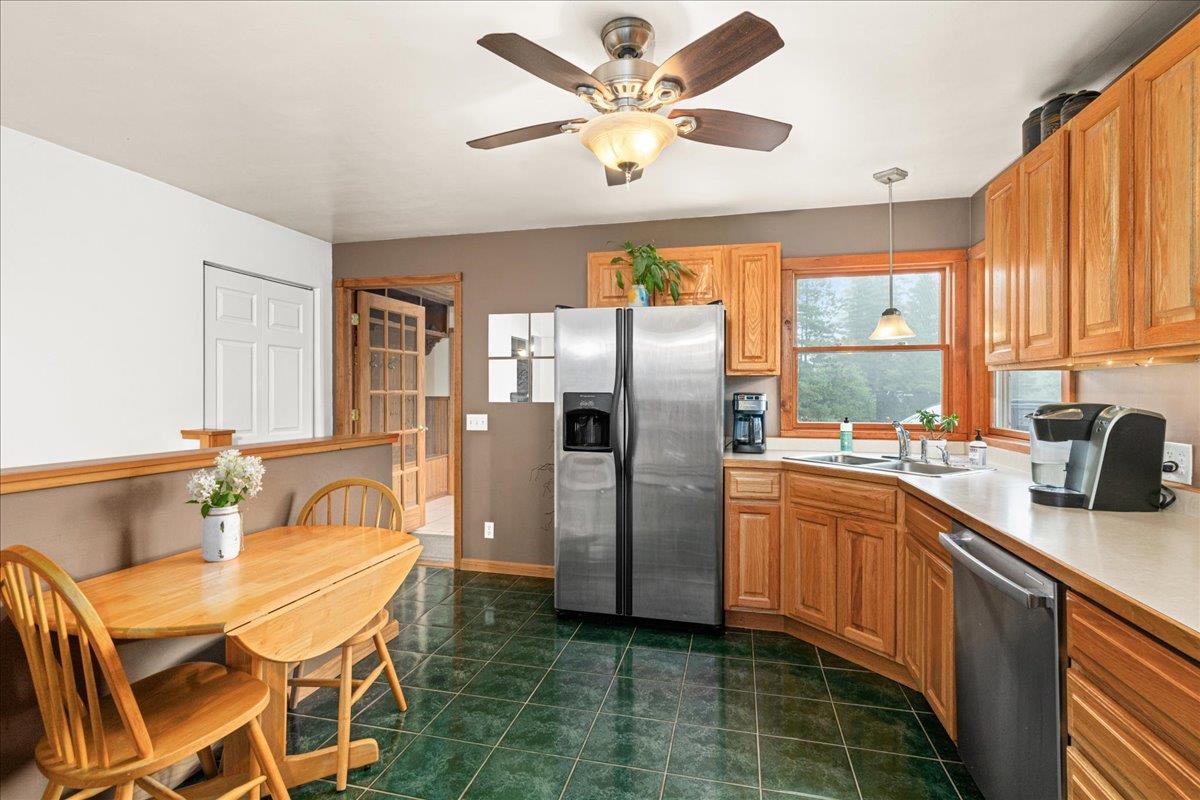 645 Stanley Road Two Harbors, MN 55616 - Photo 3 of 26 Kitchen featuring appliances with stainless steel finishes, light countertops, hanging light fixtures, dark tile patterned floors, and brown cabinets