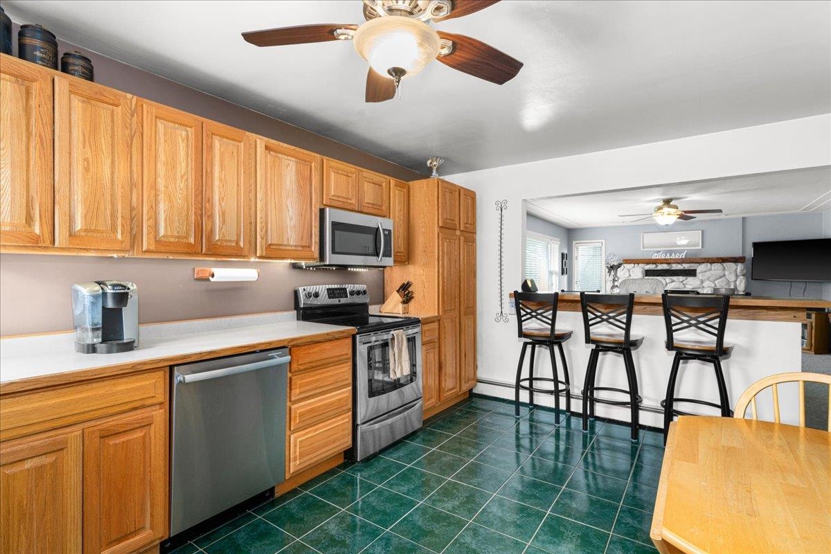 645 Stanley Road Two Harbors, MN 55616 - Photo 5 of 26 Kitchen featuring stainless steel appliances, dark tile patterned flooring, a kitchen bar, light countertops, and ceiling fan