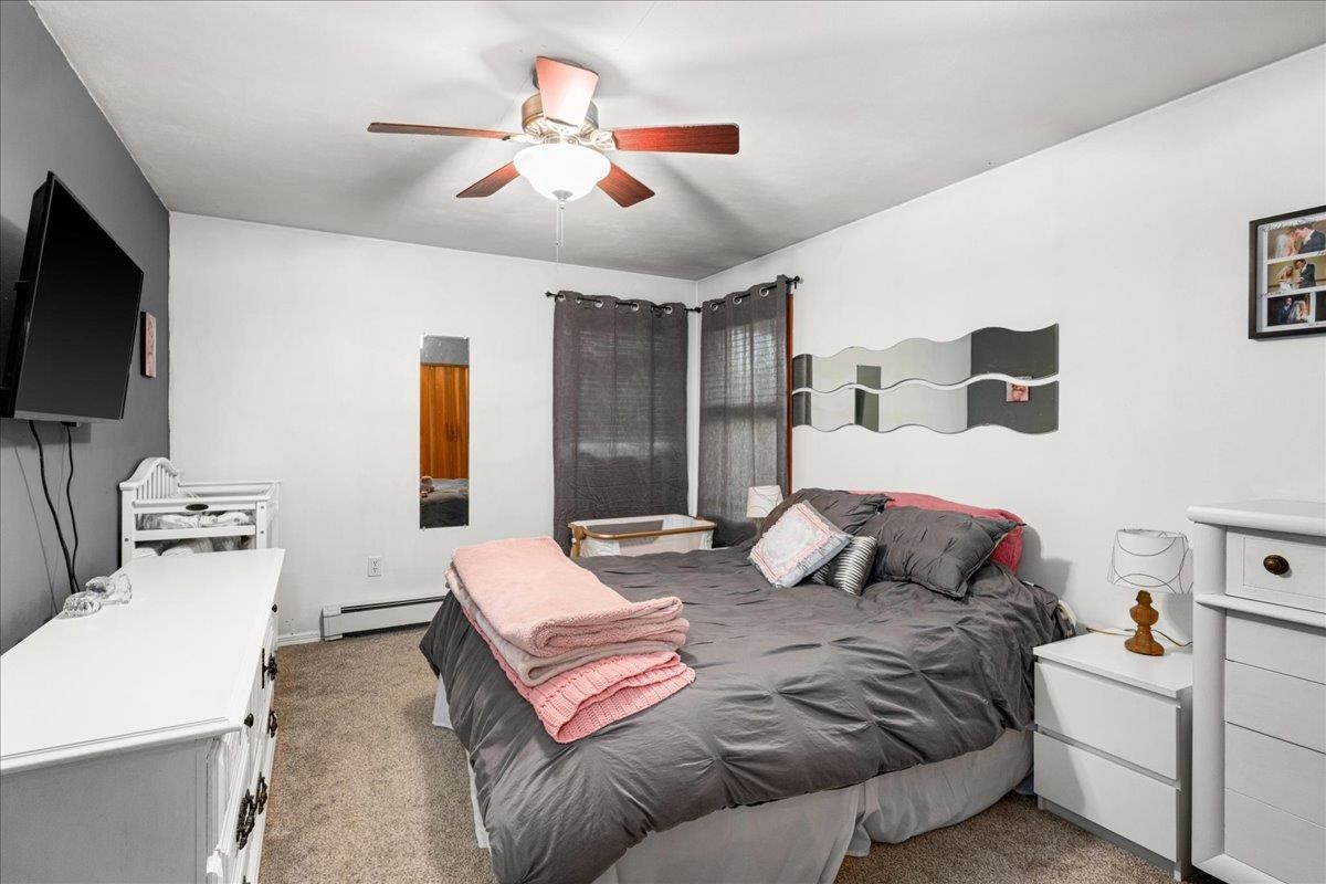 645 Stanley Road Two Harbors, MN 55616 - Photo 9 of 26 Bedroom with light colored carpet, a baseboard heating unit, and a ceiling fan
