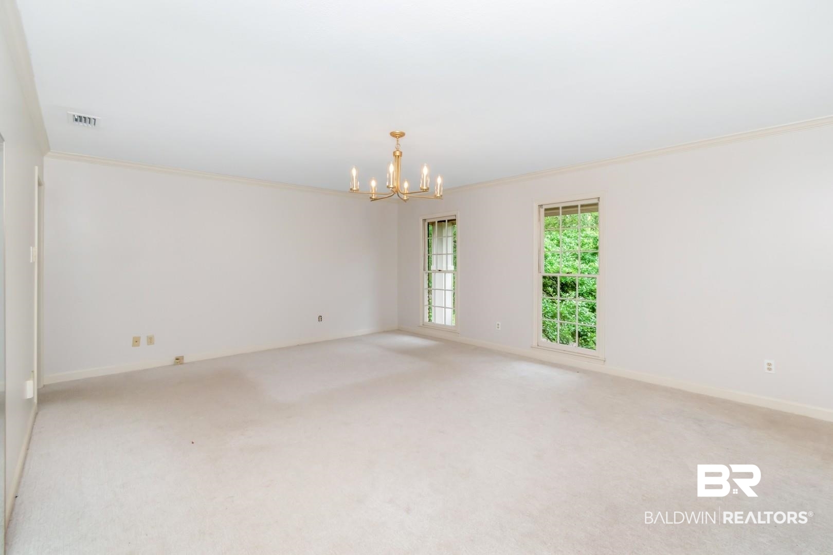 4776 Falls Church Road Mobile, AL 36608 - Photo 26 of 45 Spacious room featuring neutral carpeting, a brass chandelier, and two large windows with exterior greenery