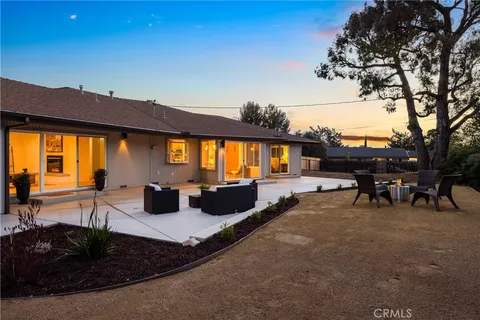 a view of a patio with table and chairs under an umbrella with large trees