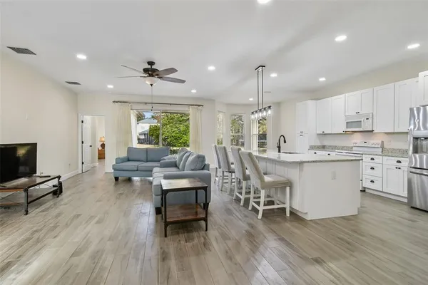a living room with stainless steel appliances granite countertop furniture wooden floor and a kitchen view