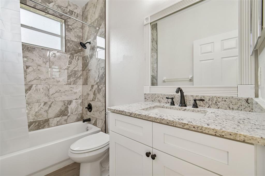 3311 Stonebridge Trail Valrico, FL 33596 - Photo 17 of 33 a bathroom with a granite countertop sink toilet mirror and bathtub