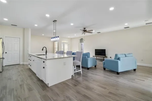 a large white kitchen with a large island oven a sink dishwasher and a fireplace with wooden floor