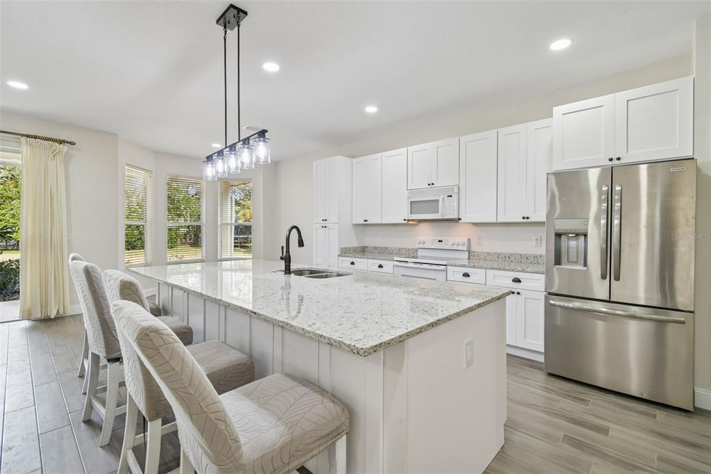 3311 Stonebridge Trail Valrico, FL 33596 - Photo 8 of 33 a kitchen with stainless steel appliances granite countertop a sink a stove a refrigerator and island with wooden floor