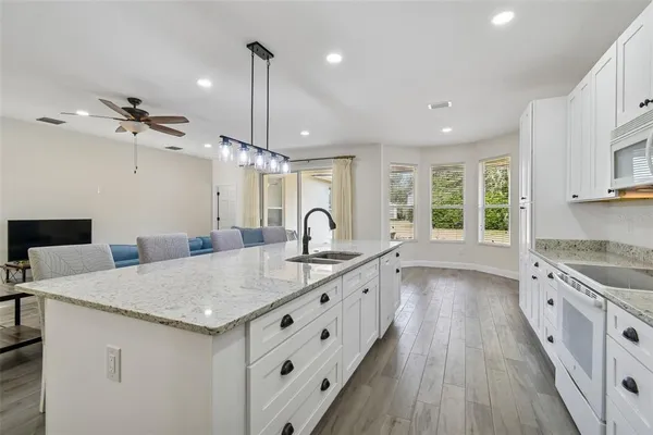 a large kitchen with kitchen island a stove a sink a center island and wooden floor