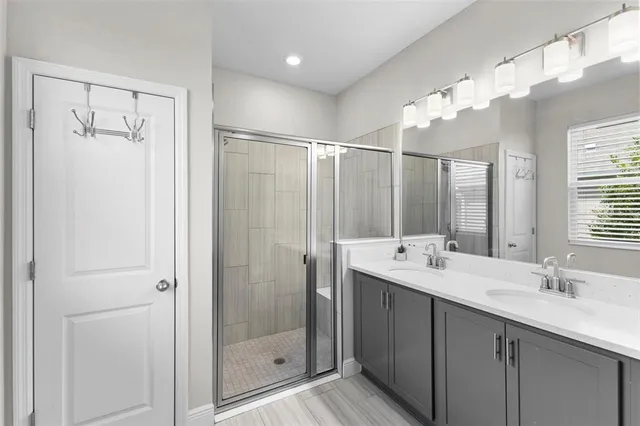 a bathroom with a double vanity sink mirror and shower