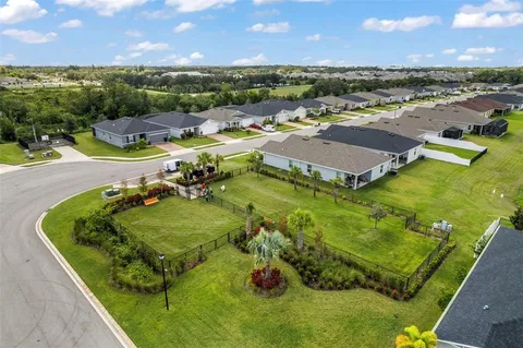 an aerial view of residential houses with outdoor space and trees