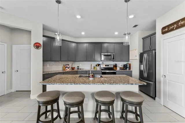 a kitchen with granite countertop a center island a sink stainless steel appliances and cabinets