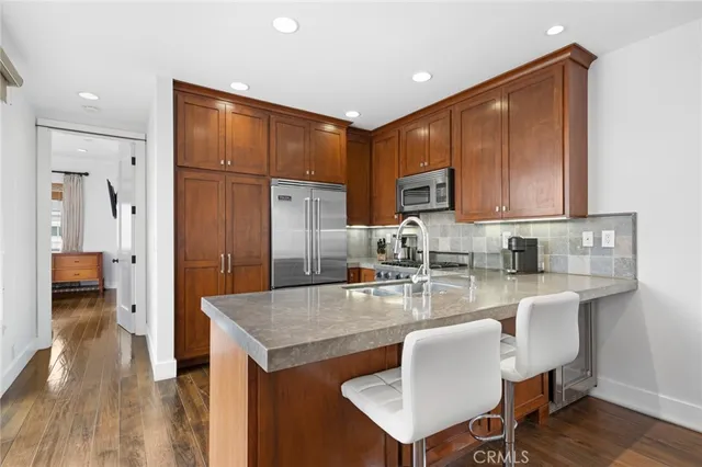 a kitchen with stainless steel appliances granite countertop a refrigerator a sink a stove and oven