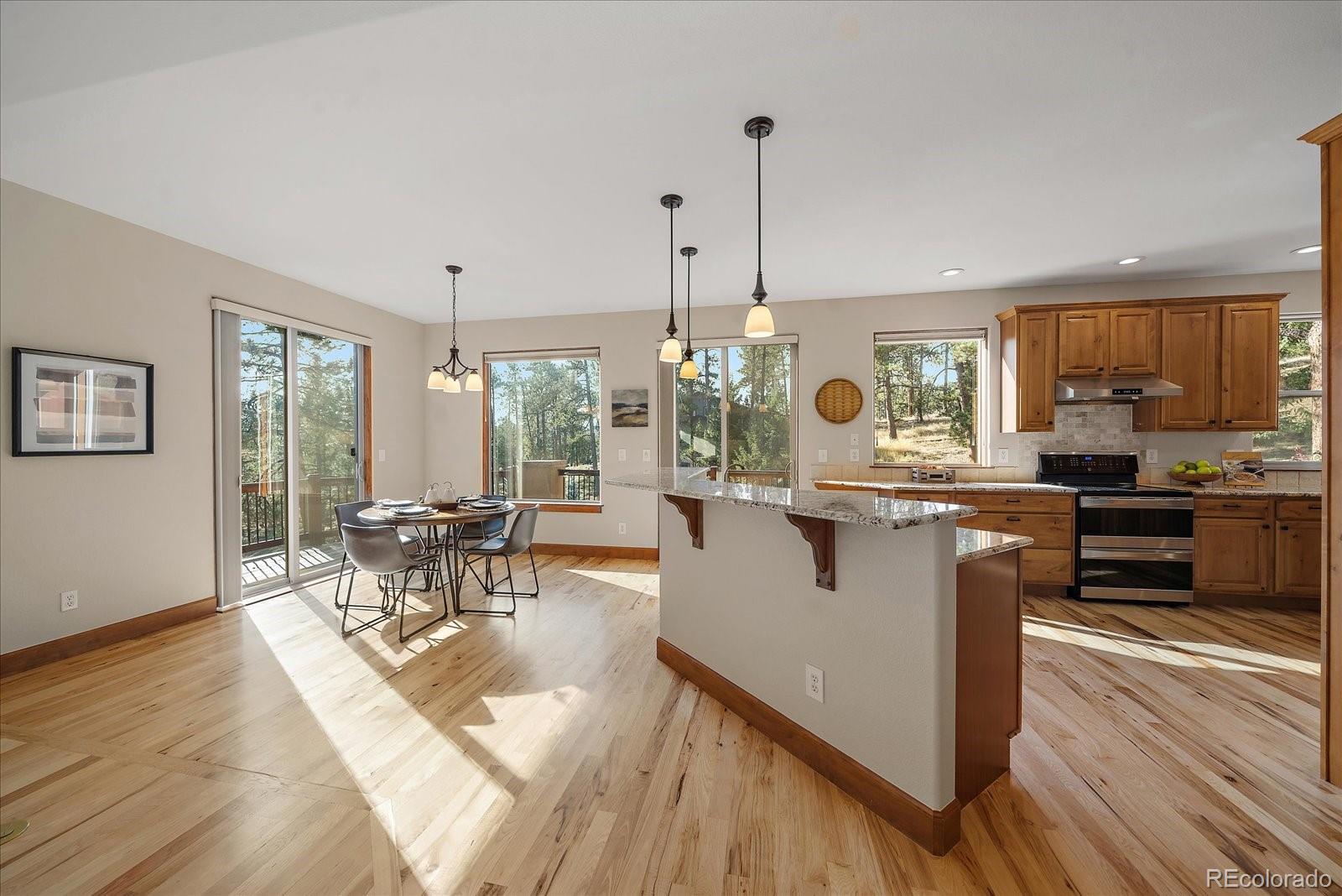 28857 Cedar Circle Evergreen, CO 80439 - Photo 13 of 50 a kitchen with stainless steel appliances granite countertop a stove top oven a sink dishwasher a dining table and chairs with wooden floor