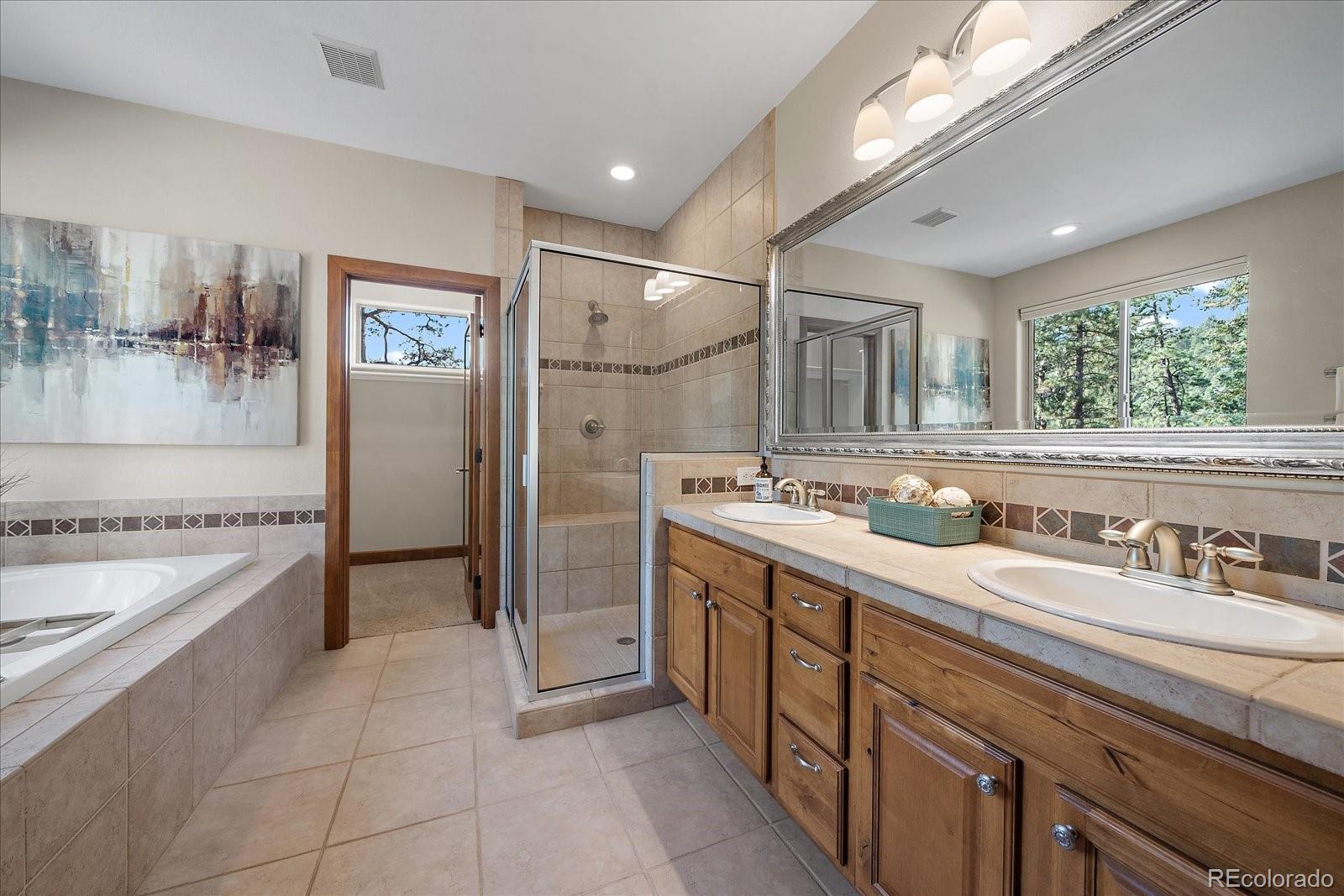 28857 Cedar Circle Evergreen, CO 80439 - Photo 23 of 50 a spacious bathroom with a granite countertop sink a mirror and shower
