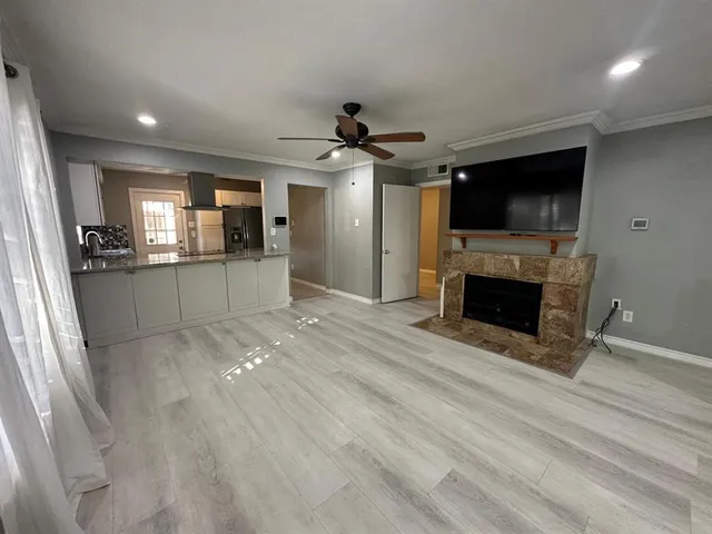 a view of a livingroom with a fireplace a window and a kitchen space