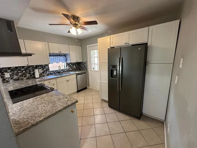 a kitchen with granite countertop a refrigerator a stove a sink dishwasher and a refrigerator