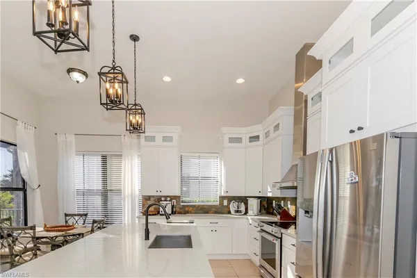 a kitchen with stainless steel appliances a refrigerator a sink dishwasher a oven and white cabinets next to a window