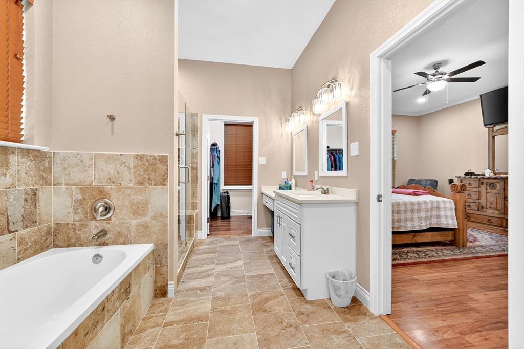 5230 Esquire Estates Road Mabank, TX 75156 - Photo 19 of 39 Spacious bathroom featuring a soaking tub with tile surround, a separate glass-enclosed shower, dual vanity with white cabinetry and integrated sinks, and tiled flooring