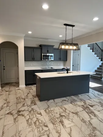 a living room with stainless steel appliances kitchen island granite countertop a sink and cabinets