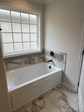 a bathroom with a bathtub and next to a window