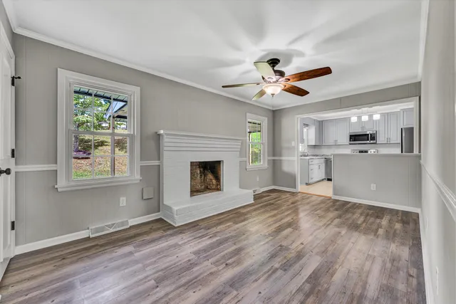a view of a kitchen with a fireplace a ceiling fan and wooden floor