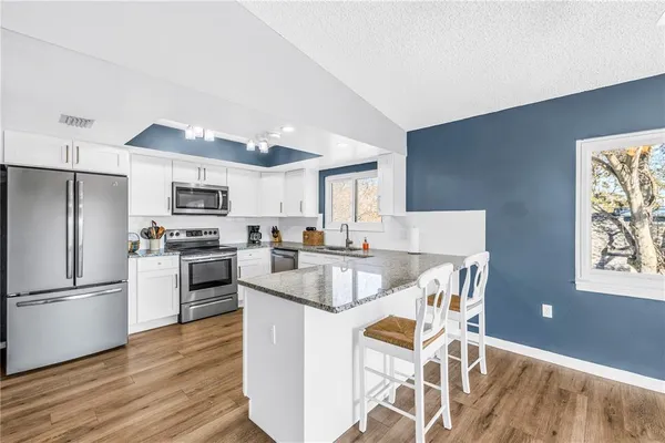 a kitchen with granite countertop a sink window and cabinets