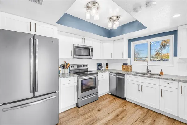 a kitchen with granite countertop a refrigerator stove and microwave
