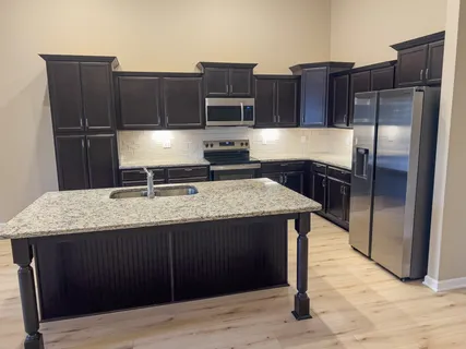 a kitchen with kitchen island granite countertop wooden cabinets and stainless steel appliances
