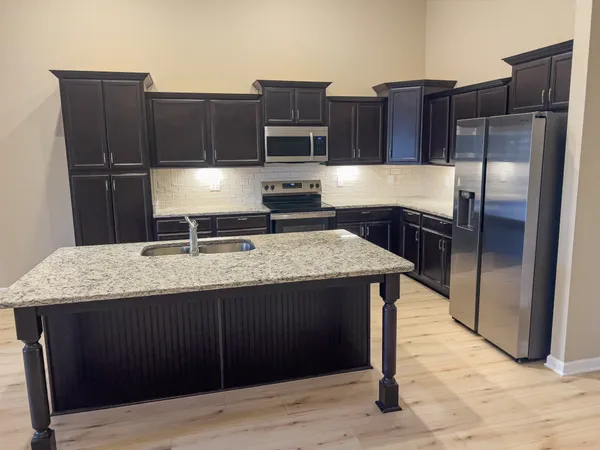 a kitchen with kitchen island granite countertop wooden cabinets and stainless steel appliances