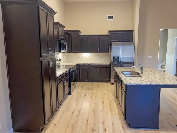 a kitchen with stainless steel appliances granite countertop a sink stove and refrigerator