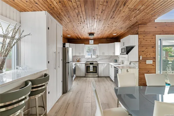 a kitchen with stainless steel appliances granite countertop a refrigerator a sink dishwasher a stove and white countertops with wooden floor
