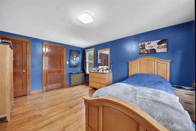 a bedroom with a bed and a dresser with wooden floor