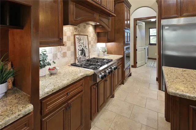a kitchen with stainless steel appliances granite countertop a stove a sink and a refrigerator