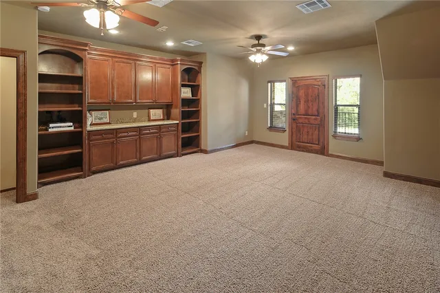 a view of an empty room with kitchen and a window